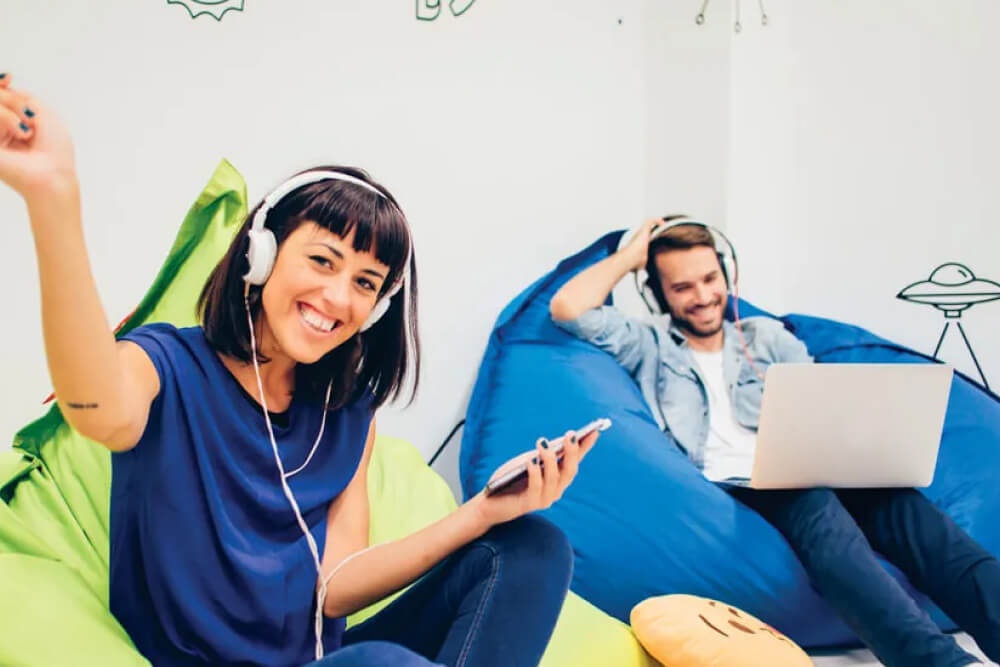 A couple enjoying music together while sitting on bean bags.