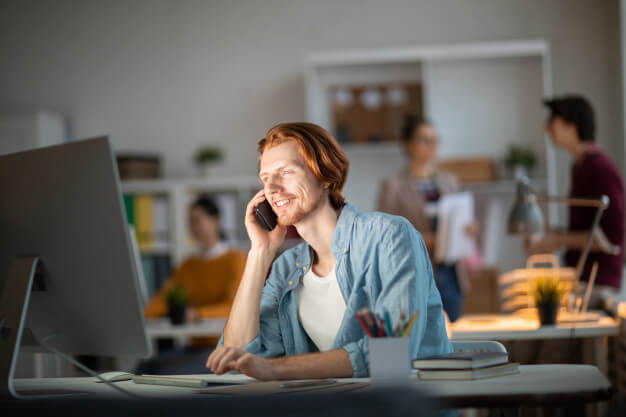 A man sitting at a desk, engaged in a phone conversation.