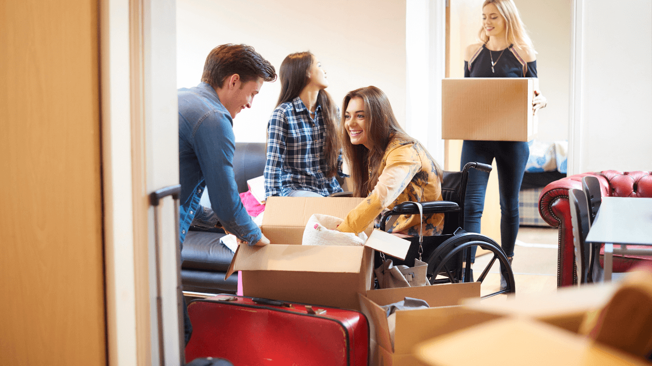 A woman in a wheelchair gets help from other people moving boxes together.