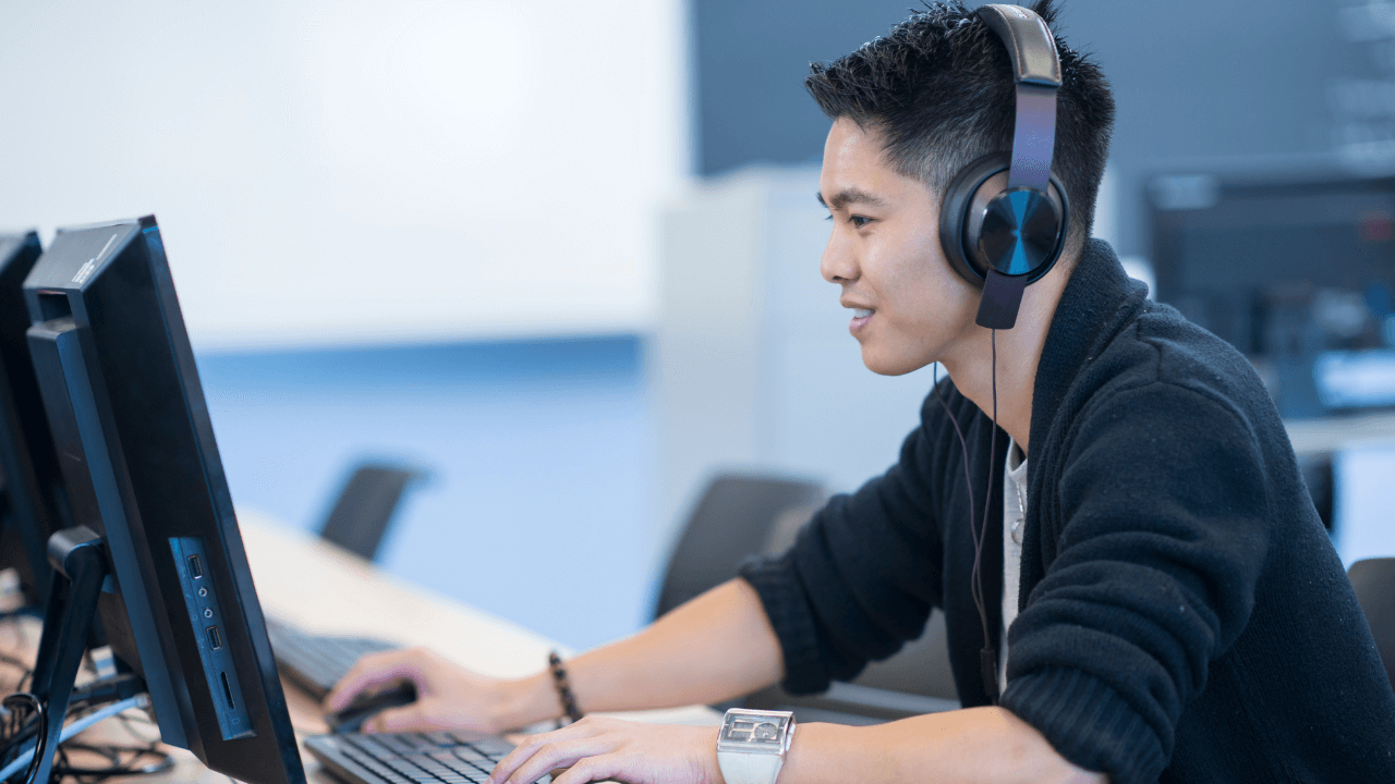 A college student taking an exam with headphones on.