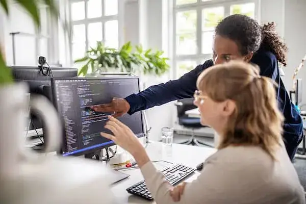 Two women collaborating on a computer, engaged in a productive work session.